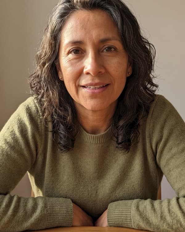 Alma Reyes sentada a la mesa de su casa, con un rosario delante.